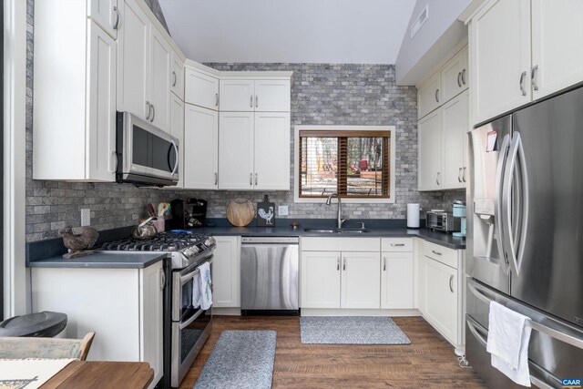 kitchen featuring a sink, visible vents, appliances with stainless steel finishes, backsplash, and dark countertops