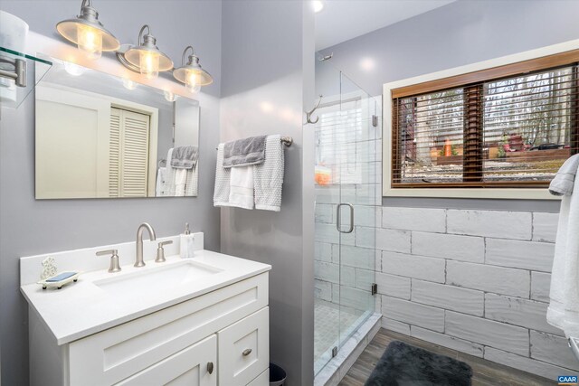 full bath featuring a shower stall, vanity, and wood finished floors