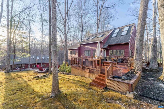 exterior space with a shingled roof, a front yard, and a wooden deck