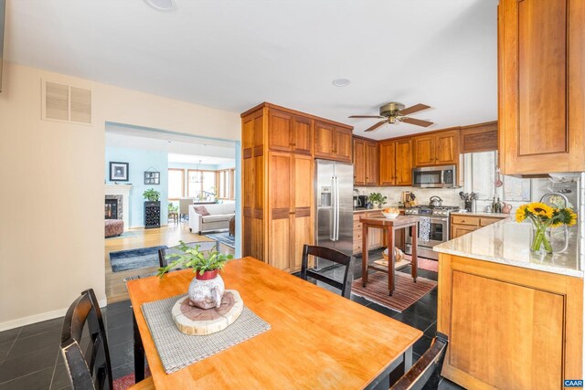 interior space featuring baseboards, visible vents, a glass covered fireplace, stainless steel appliances, and dark tile patterned floors