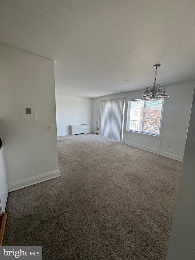 unfurnished living room featuring carpet flooring, a notable chandelier, and baseboards