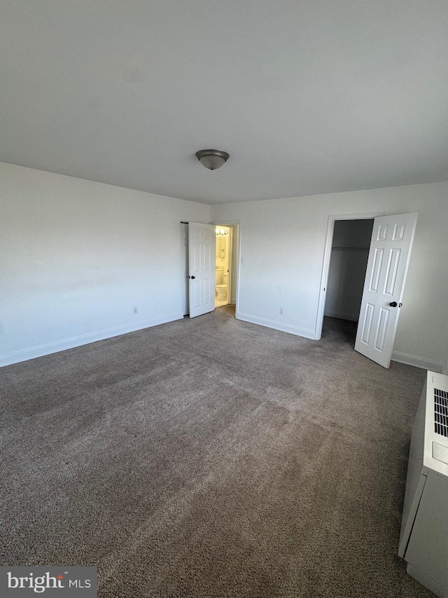 unfurnished bedroom featuring dark carpet and baseboards