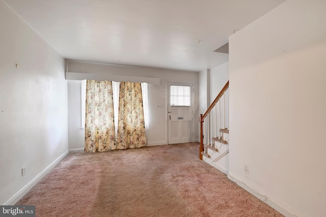 foyer featuring carpet floors, baseboards, and stairway