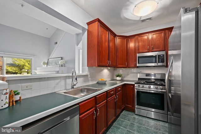 kitchen featuring a sink, visible vents, appliances with stainless steel finishes, backsplash, and reddish brown cabinets