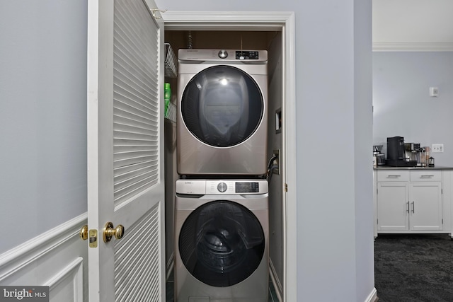 clothes washing area with laundry area, dark carpet, and stacked washer and clothes dryer