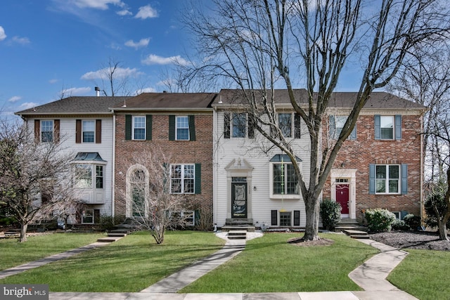 view of front of house featuring brick siding and a front yard