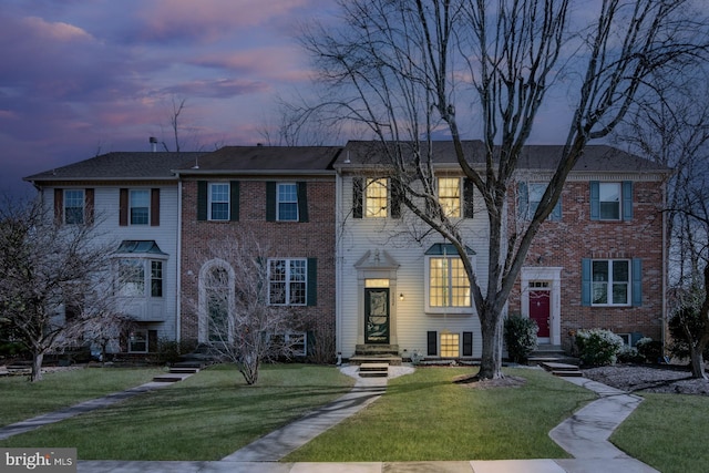 view of front of property featuring a lawn and brick siding