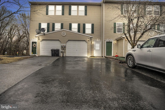 townhome / multi-family property with a garage and aphalt driveway