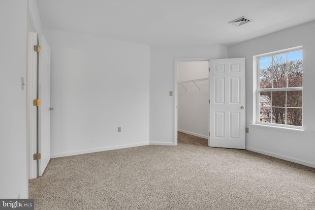 unfurnished bedroom featuring baseboards, multiple windows, visible vents, and carpet flooring