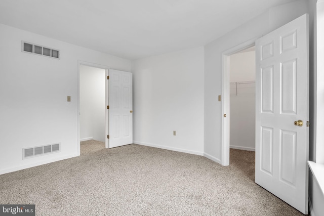 unfurnished bedroom with visible vents, a spacious closet, and carpet flooring