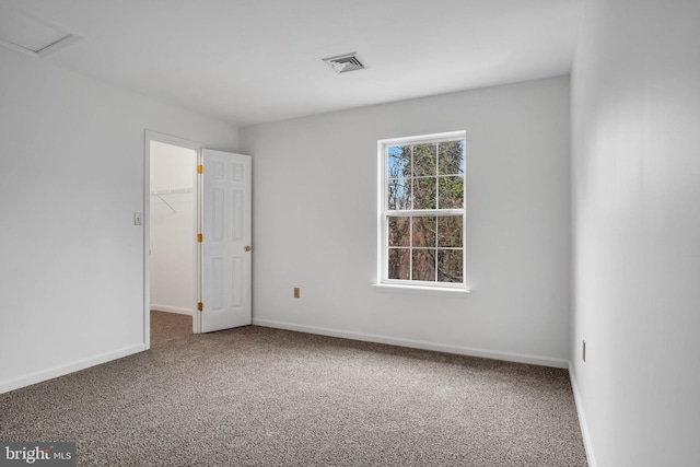 empty room featuring carpet floors, visible vents, and baseboards