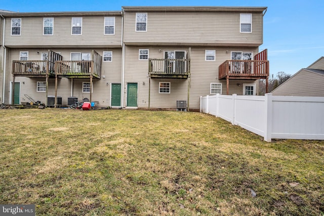 back of house featuring cooling unit, a lawn, and fence