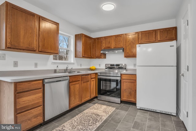 kitchen featuring light countertops, appliances with stainless steel finishes, brown cabinetry, and under cabinet range hood