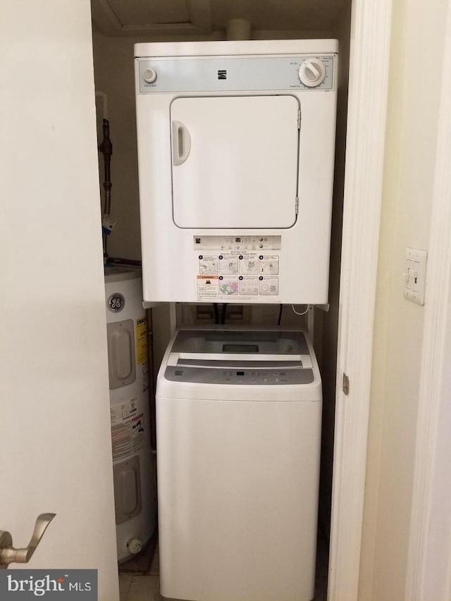 washroom featuring water heater, laundry area, and stacked washing maching and dryer