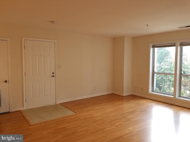 unfurnished room with baseboards, visible vents, and light wood finished floors