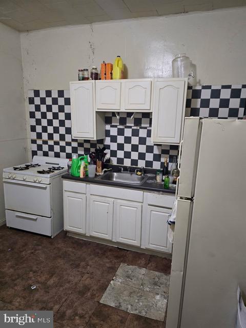 kitchen with white appliances, white cabinets, and a sink