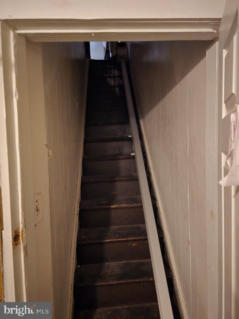 stairway featuring wooden walls