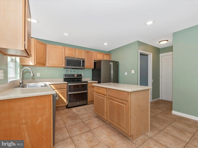 kitchen with a sink, light brown cabinetry, light countertops, appliances with stainless steel finishes, and a center island