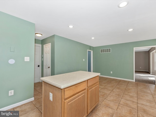 kitchen featuring visible vents, a center island, baseboards, light countertops, and light tile patterned flooring