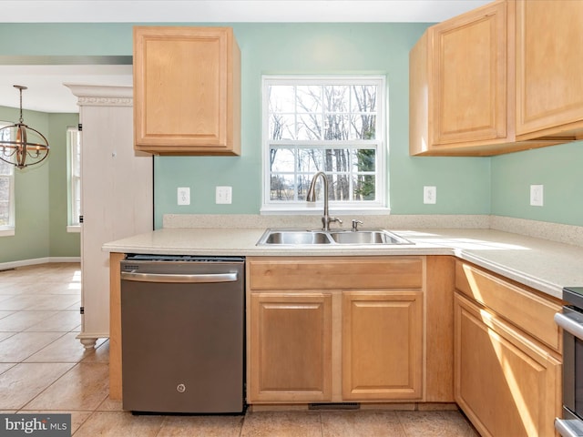 kitchen featuring stainless steel dishwasher, light countertops, light brown cabinetry, and a sink