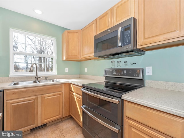 kitchen featuring light tile patterned floors, a sink, light brown cabinetry, light countertops, and stainless steel appliances