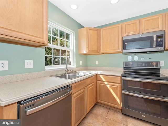 kitchen with light brown cabinets, light countertops, appliances with stainless steel finishes, light tile patterned flooring, and a sink