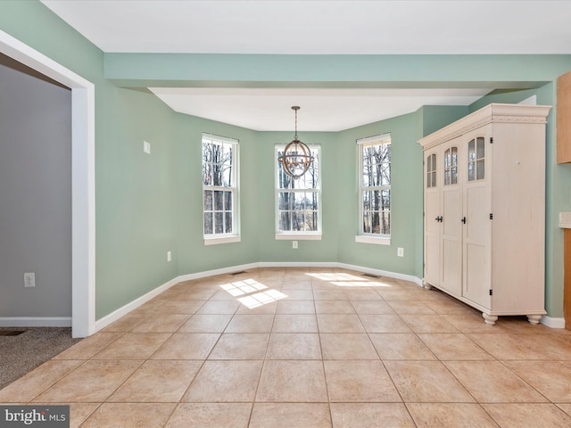 unfurnished dining area with light tile patterned floors, a notable chandelier, and baseboards