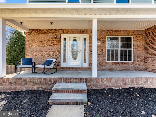 property entrance with brick siding and covered porch