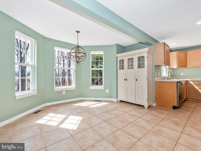 kitchen featuring light countertops, light tile patterned floors, a healthy amount of sunlight, and baseboards