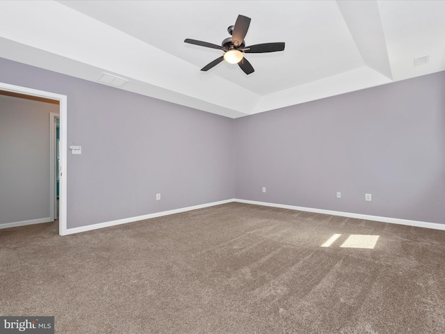 carpeted empty room featuring baseboards, a raised ceiling, and ceiling fan