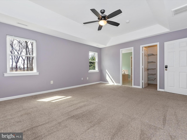 unfurnished bedroom featuring visible vents, carpet floors, baseboards, and a walk in closet