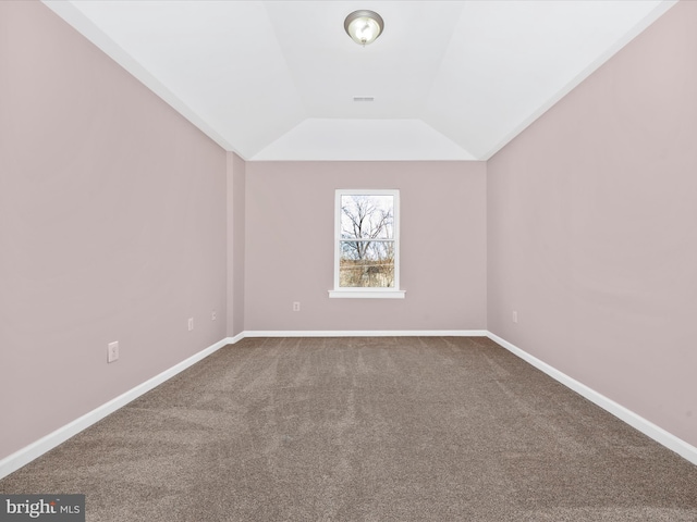 spare room featuring visible vents, dark carpet, lofted ceiling, and baseboards