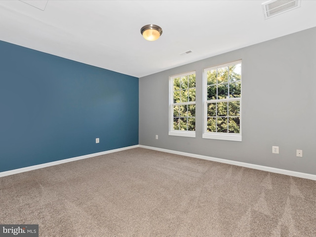 carpeted spare room with visible vents and baseboards