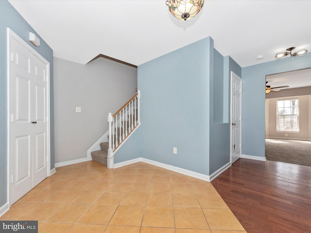 interior space with stairs, wood finished floors, a ceiling fan, and baseboards