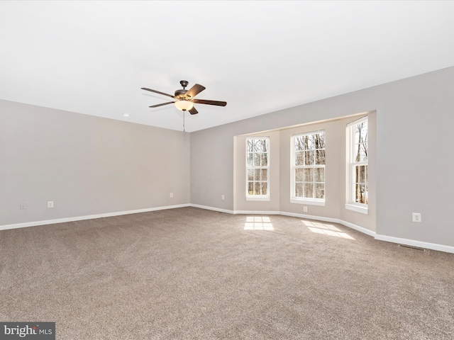 unfurnished room with visible vents, carpet floors, baseboards, and a ceiling fan