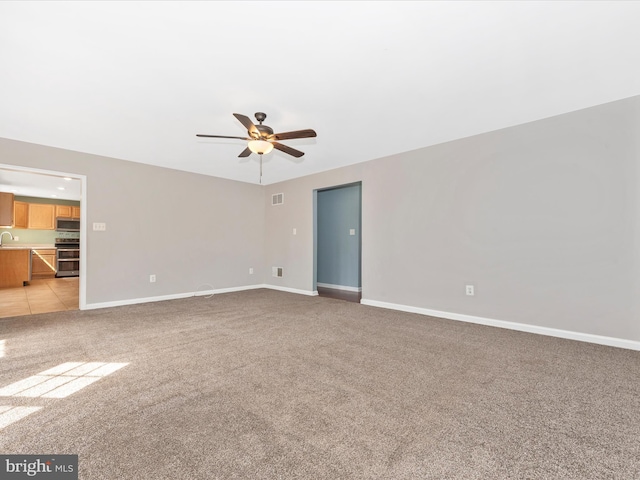 unfurnished living room featuring baseboards, light carpet, visible vents, and a ceiling fan