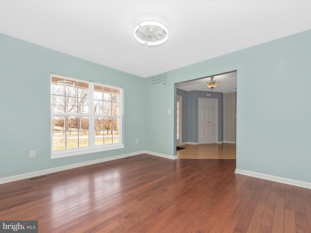 unfurnished room featuring visible vents, baseboards, and wood-type flooring