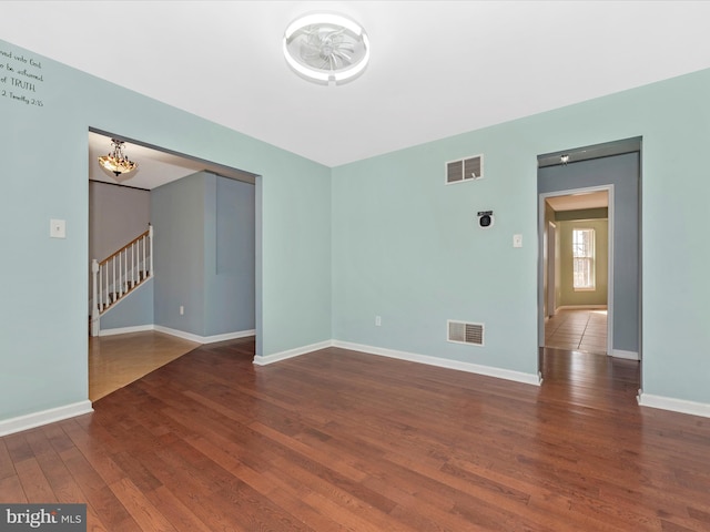 empty room featuring visible vents, baseboards, and hardwood / wood-style floors