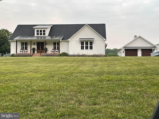 modern inspired farmhouse featuring a standing seam roof, a porch, a front lawn, an outdoor structure, and metal roof