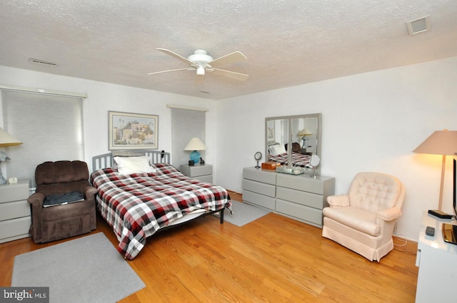 bedroom featuring visible vents, a textured ceiling, and wood finished floors