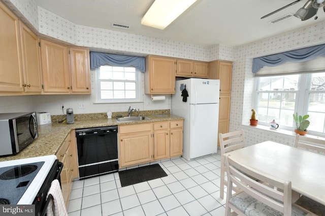 kitchen featuring wallpapered walls, black dishwasher, stainless steel microwave, freestanding refrigerator, and a sink