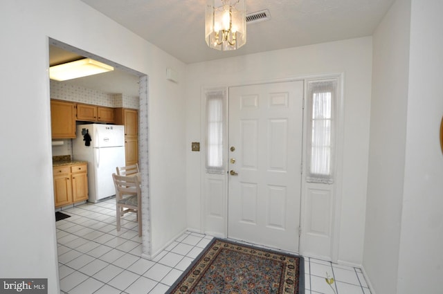 foyer featuring light tile patterned floors, a chandelier, visible vents, and baseboards