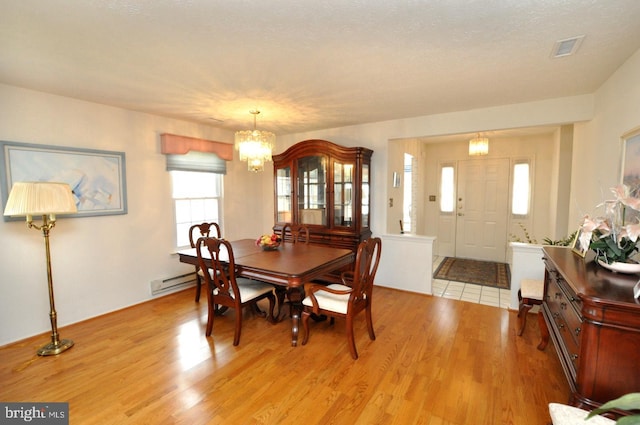 dining area featuring an inviting chandelier, light wood-style flooring, and visible vents