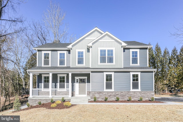 craftsman-style house with covered porch, stone siding, board and batten siding, and roof with shingles