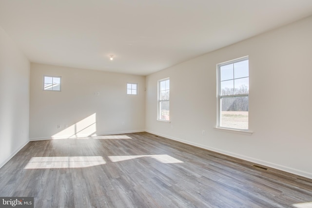 empty room with baseboards, visible vents, and wood finished floors