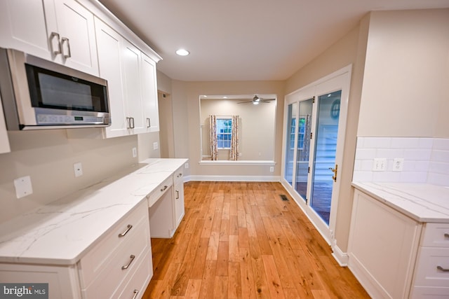 622 Hastings Rd, Baltimore, MD 21286 - kitchen with stainless steel microwave, white cabinets, light wood-type flooring, light stone countertops, and ceiling fan