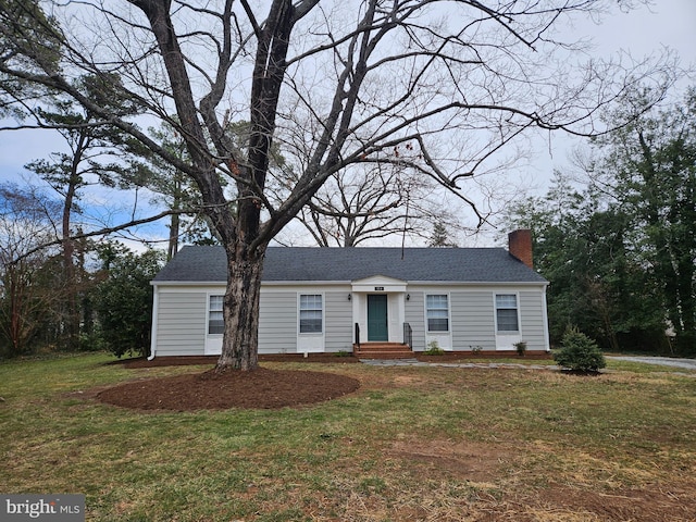 view of front facade featuring a front yard, roof with shingles, and a chimney