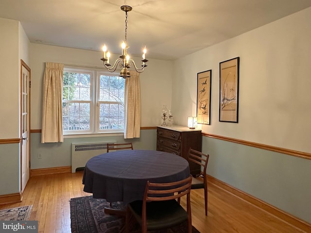 dining space with light wood-type flooring, radiator heating unit, baseboards, and a notable chandelier