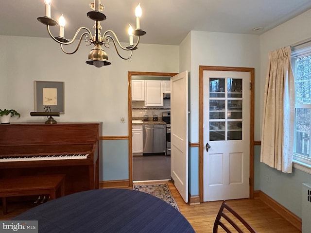 bedroom with baseboards, light wood-type flooring, and a notable chandelier