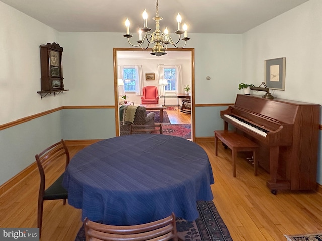 dining area with baseboards, wood finished floors, and a notable chandelier